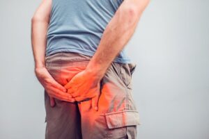 Man with hemorrhoids holding his butt in pain in a white background